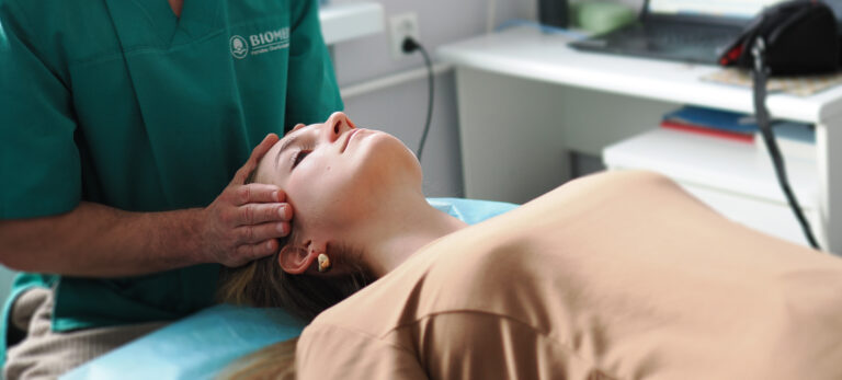 Terapeuta delikatnie dotykający głowy pacjentki podczas terapii czaszkowo-krzyżowej w przychodni Biomed