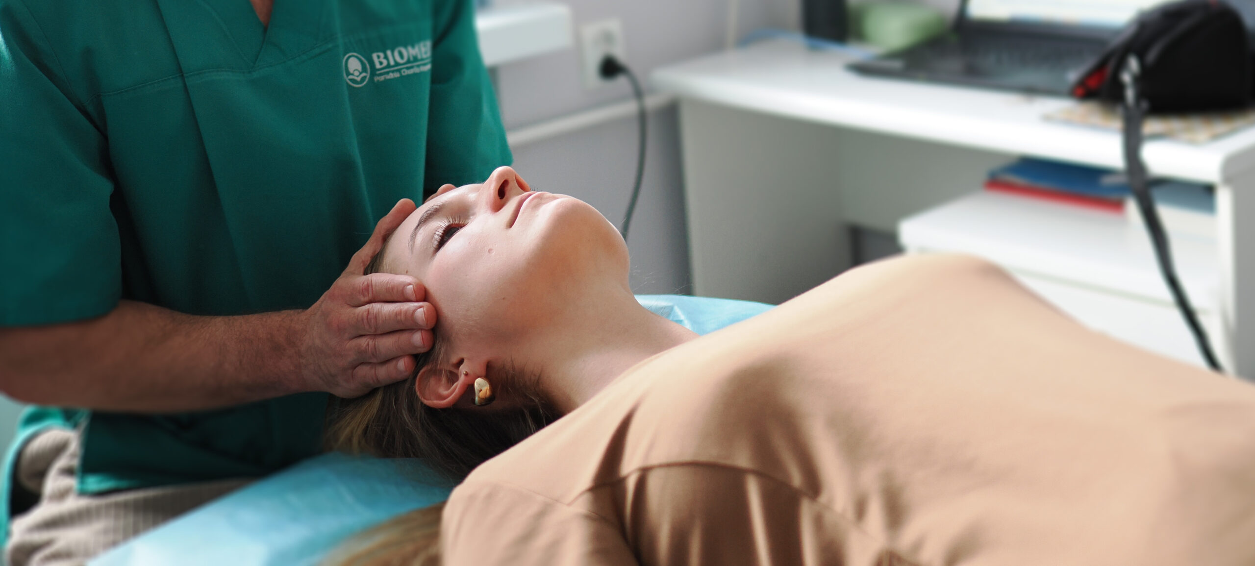 Terapeuta delikatnie dotykający głowy pacjentki podczas terapii czaszkowo-krzyżowej w przychodni Biomed